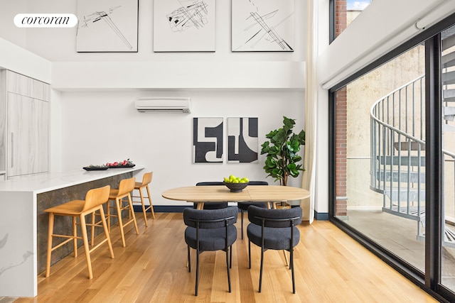 123 Clinton Ave Unit 4B, New York City, NY 11205 - dining room with a wall mounted AC, light wood-type flooring, a towering ceiling, and baseboards