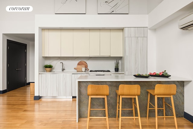 123 Clinton Ave Unit 4B, New York City, NY 11205 - kitchen featuring a wall mounted AC, modern cabinets, a kitchen bar, light wood-style flooring, and dishwashing machine