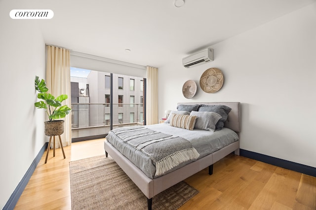 123 Clinton Ave Unit 4B, New York City, NY 11205 - bedroom featuring a wall unit AC, light wood-style flooring, and baseboards