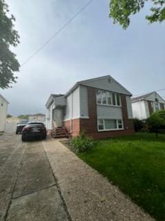 10561 Flatlands 7th St, New York City, NY 11236 - view of property exterior featuring driveway, brick siding, and a yard