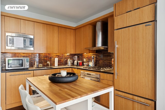 70 Little W St Unit 6J, New York City, NY 10280 - kitchen with built in appliances, wall chimney range hood, wood counters, decorative backsplash, and a breakfast bar area