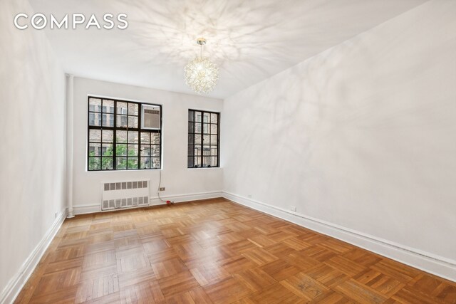 116 Pinehurst Ave Unit H32, New York City, NY 10033 - empty room with radiator heating unit, a chandelier, and baseboards