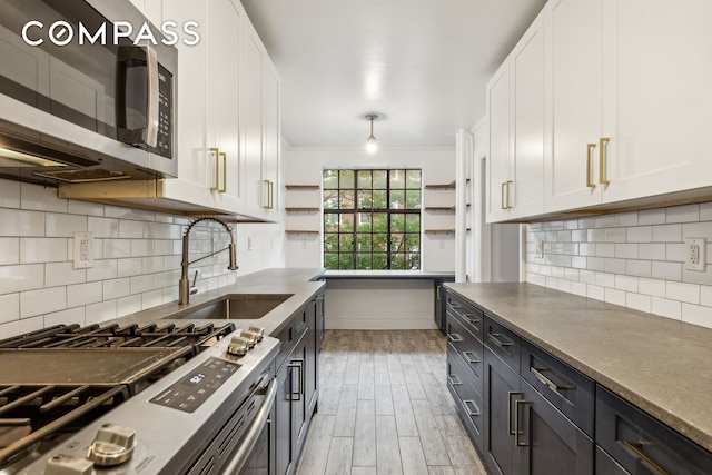 116 Pinehurst Ave Unit H32, New York City, NY 10033 - kitchen featuring appliances with stainless steel finishes, white cabinetry, a sink, baseboards, and light wood finished floors
