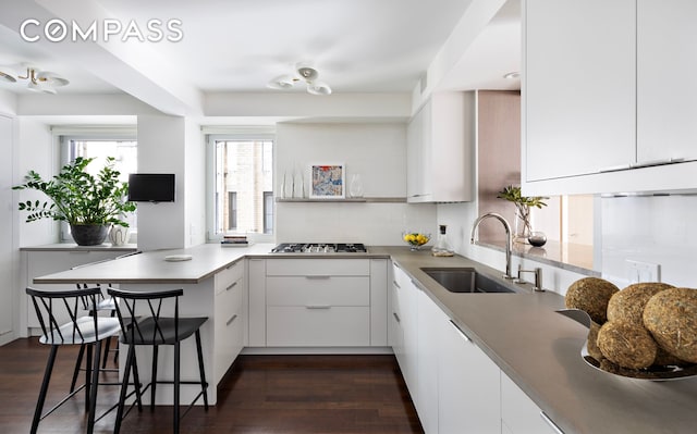 45 E 72nd St Unit 9Bc, New York City, NY 10021 - kitchen with a sink, stainless steel gas stovetop, white cabinets, a peninsula, and modern cabinets