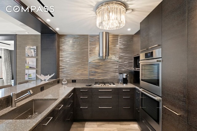 188 E 70th St Unit 10Cb, New York City, NY 10021 - kitchen featuring stainless steel double oven, a sink, stone counters, wall chimney exhaust hood, and a chandelier