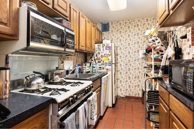 77 W 55th St Unit 7F, New York City, NY 10019 - kitchen with wallpapered walls, stainless steel microwave, gas range oven, dark countertops, and dark tile patterned floors