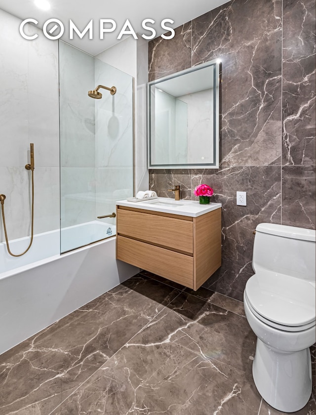 420 E 75th St Unit 3, New York City, NY 10021 - bathroom with tile walls, marble tiled flooring, toilet, vanity, and bathtub / shower combination