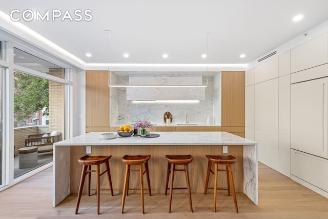 420 E 75th St Unit 3, New York City, NY 10021 - kitchen with modern cabinets, a sink, a kitchen bar, a large island, and recessed lighting