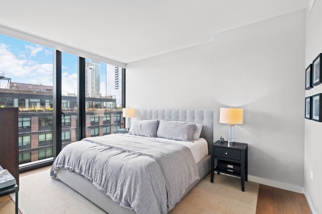 21-30 44th Dr Unit 7C, New York City, NY 11101 - bedroom with a view of city, multiple windows, wood finished floors, and baseboards
