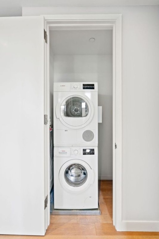 21-30 44th Dr Unit 7C, New York City, NY 11101 - laundry area with stacked washing machine and dryer and wood finished floors