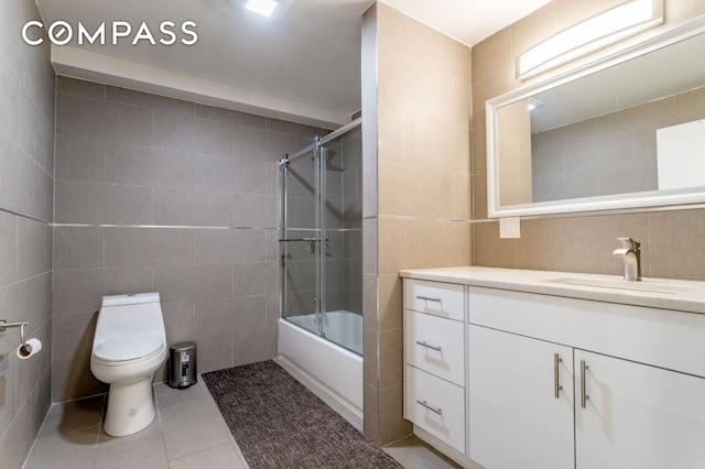 212 E 70th St Unit B, New York City, NY 10021 - bathroom with tile walls, vanity, tile patterned floors, bath / shower combo with glass door, and decorative backsplash