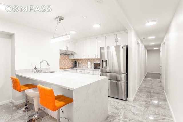 212 E 70th St Unit B, New York City, NY 10021 - kitchen with stainless steel fridge with ice dispenser, under cabinet range hood, a breakfast bar area, a peninsula, and white cabinets