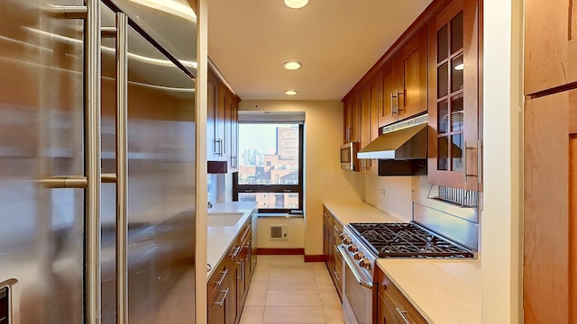 415 E 54th St Unit 19-G, New York City, NY 10022 - kitchen featuring premium appliances, brown cabinets, recessed lighting, under cabinet range hood, and light tile patterned floors