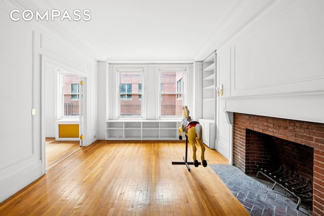 50 W 67th St Unit 4E, New York City, NY 10023 - living area featuring light wood-style flooring, a fireplace, built in features, and crown molding