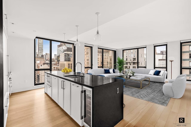 160 E 22nd St Unit 18-A, New York City, NY 10010 - kitchen with a sink, wine cooler, dark countertops, light wood-style flooring, and a wall of windows