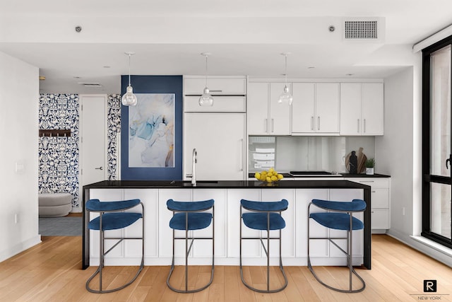160 E 22nd St Unit 18-A, New York City, NY 10010 - kitchen with a sink, a breakfast bar, white cabinetry, and light wood-style flooring
