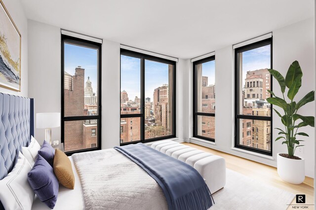160 E 22nd St Unit 18-A, New York City, NY 10010 - bedroom with multiple windows, wood finished floors, a view of skyline, and floor to ceiling windows