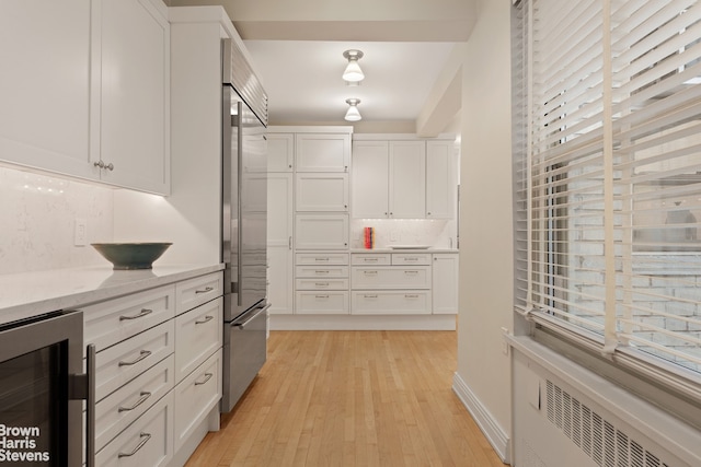 3 E 71st St Unit 7/8C, New York City, NY 10021 - kitchen with wine cooler, radiator, white cabinetry, light wood-style flooring, and high end fridge