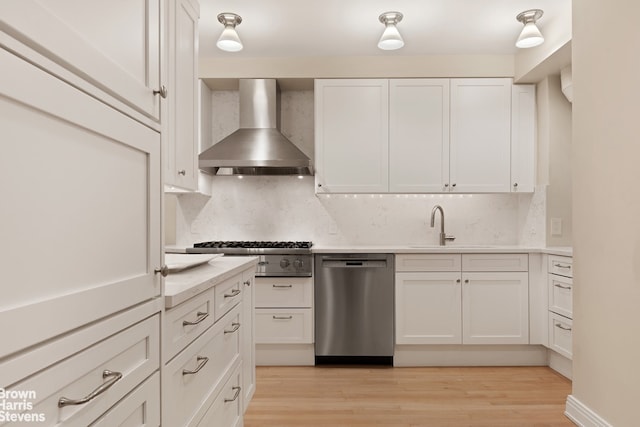 3 E 71st St Unit 7/8C, New York City, NY 10021 - kitchen featuring appliances with stainless steel finishes, wall chimney exhaust hood, a sink, white cabinets, and backsplash