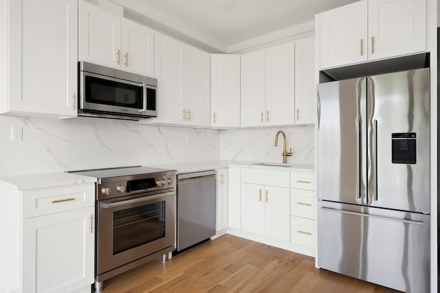 78 Harman St Unit 2-F, New York City, NY 11221 - kitchen featuring appliances with stainless steel finishes, white cabinetry, light wood finished floors, and tasteful backsplash