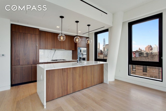 242 Broome St Unit 7D, New York City, NY 10002 - kitchen featuring modern cabinets, white gas cooktop, light wood-style floors, and backsplash