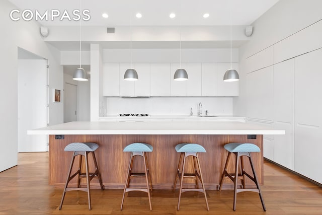 175 E Broadway Unit 8B, New York City, NY 10002 - kitchen with modern cabinets, white cabinetry, a sink, light countertops, and a kitchen bar