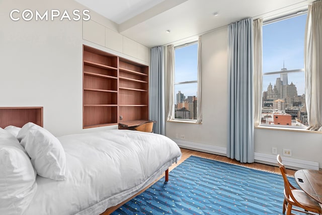 175 E Broadway Unit 8B, New York City, NY 10002 - bedroom with wood finished floors, a skyline view, and a baseboard radiator