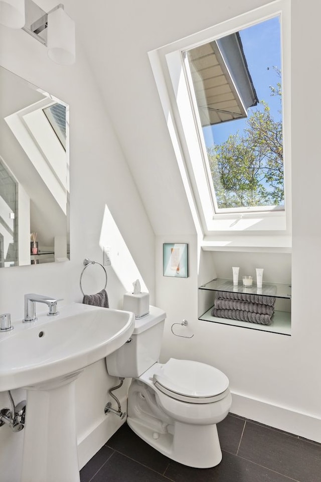 685 E 22nd St, New York City, NY 11210 - bathroom with toilet, tile patterned flooring, a skylight, and baseboards