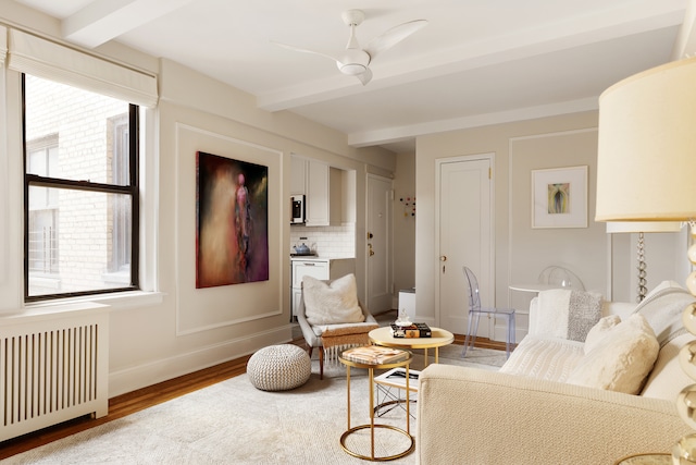 74 W 68th St Unit 7F, New York City, NY 10023 - living room with radiator, beam ceiling, wood finished floors, a ceiling fan, and baseboards