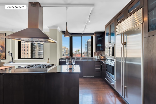 280 Park Ave S Unit 18Ef, New York City, NY 10010 - kitchen with built in appliances, island exhaust hood, track lighting, glass insert cabinets, and dark wood-type flooring