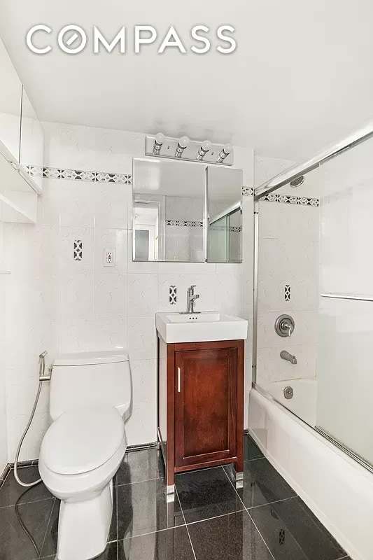 153 E 57th St Unit 17F, New York City, NY 10022 - bathroom featuring tile walls, vanity, toilet, and shower / washtub combination