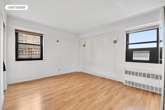 33-43 14th St Unit 12B, New York City, NY 11106 - unfurnished room featuring radiator, plenty of natural light, light wood-style floors, and cooling unit