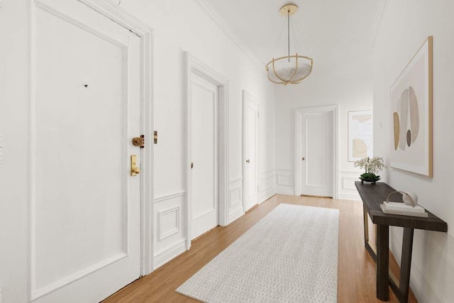 150 E 72nd St Unit 6S, New York City, NY 10021 - hall with a chandelier, light wood finished floors, ornamental molding, a decorative wall, and a wainscoted wall