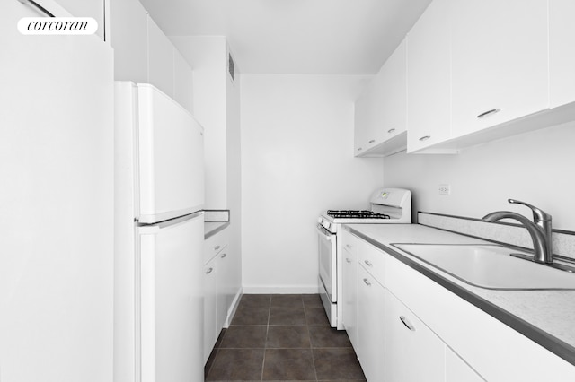 205 W End Ave Unit 9R, New York City, NY 10023 - kitchen with white appliances, a sink, white cabinets, dark tile patterned floors, and baseboards