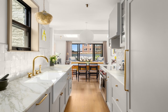 15 Jones St Unit 6A, New York City, NY 10014 - kitchen featuring high end stainless steel range oven, backsplash, light stone counters, and glass insert cabinets