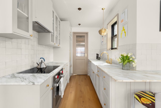15 Jones St Unit 6A, New York City, NY 10014 - kitchen featuring oven, black electric stovetop, white cabinets, and decorative backsplash