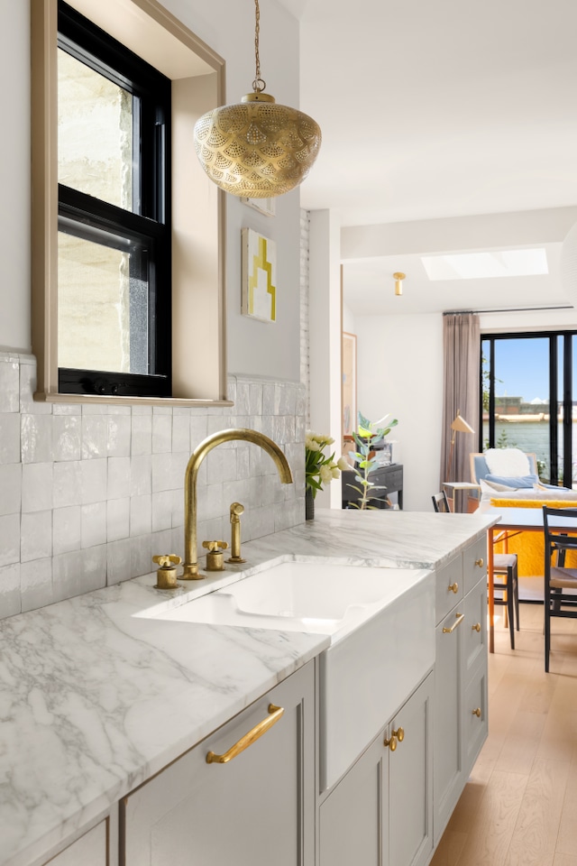 15 Jones St Unit 6A, New York City, NY 10014 - kitchen with tasteful backsplash, a skylight, a sink, light stone countertops, and hanging light fixtures