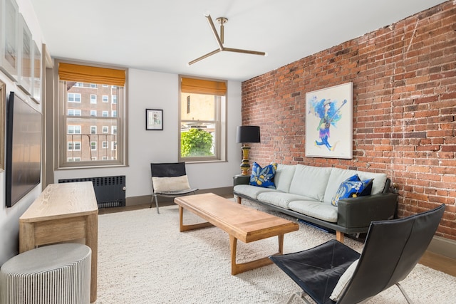 15 Jones St Unit 6A, New York City, NY 10014 - living room with radiator, brick wall, baseboards, and wood finished floors