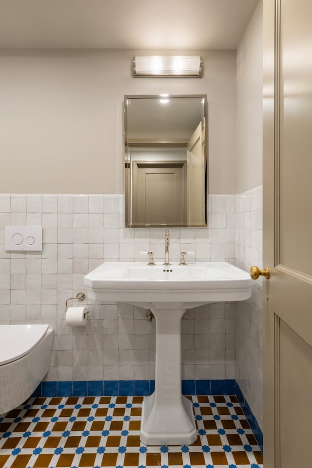 15 Jones St Unit 6A, New York City, NY 10014 - half bath featuring tile walls, toilet, a wainscoted wall, and tile patterned floors