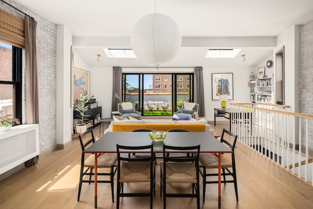 15 Jones St Unit 6A, New York City, NY 10014 - dining area with a skylight, light wood-style floors, brick wall, and baseboards
