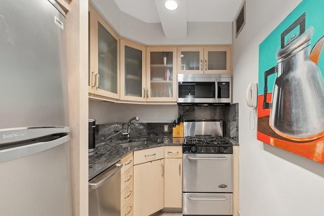 205 E 63rd St Unit 5H, New York City, NY 10065 - kitchen with stainless steel appliances, a sink, dark stone counters, glass insert cabinets, and cream cabinetry