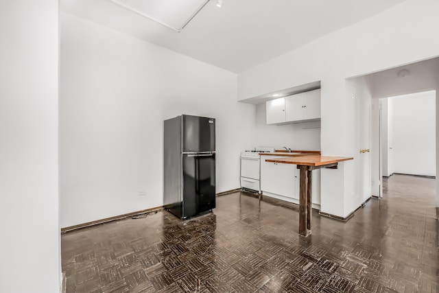 263 Bennett Ave Unit 1C, New York City, NY 10040 - kitchen with freestanding refrigerator, butcher block countertops, white cabinetry, baseboards, and gas range gas stove