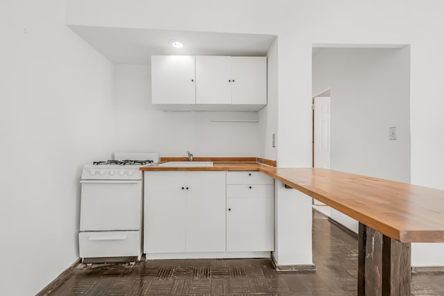 263 Bennett Ave Unit 1C, New York City, NY 10040 - kitchen with white gas range oven, white cabinets, butcher block countertops, a sink, and baseboards