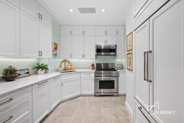 303 W 80th St Unit 2B1B, New York City, NY 10024 - kitchen with premium appliances, a sink, white cabinets, recessed lighting, and light stone counters