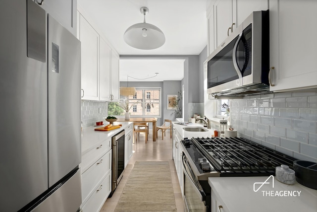 130 E 63rd St Unit 4E, New York City, NY 10065 - kitchen with appliances with stainless steel finishes, decorative backsplash, beverage cooler, white cabinetry, and light countertops