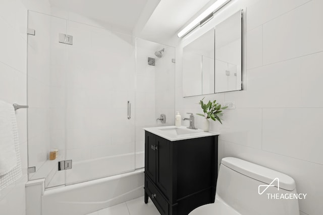 130 E 63rd St Unit 4E, New York City, NY 10065 - bathroom featuring vanity, shower / bath combination with glass door, and tile walls