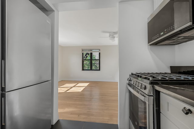 295 Bennett Ave Unit 7C, New York City, NY 10040 - kitchen with appliances with stainless steel finishes, white cabinets, wood finished floors, and ceiling fan