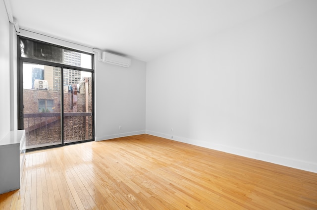 184 Thompson St Unit 5B, New York City, NY 10012 - unfurnished room with a wall unit AC, light wood finished floors, and baseboards