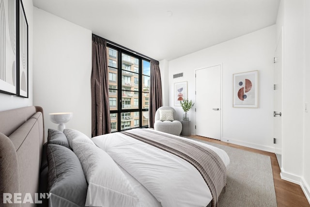 261 W 25th St Unit 8A, New York City, NY 10001 - bedroom featuring expansive windows, dark wood-style flooring, and baseboards