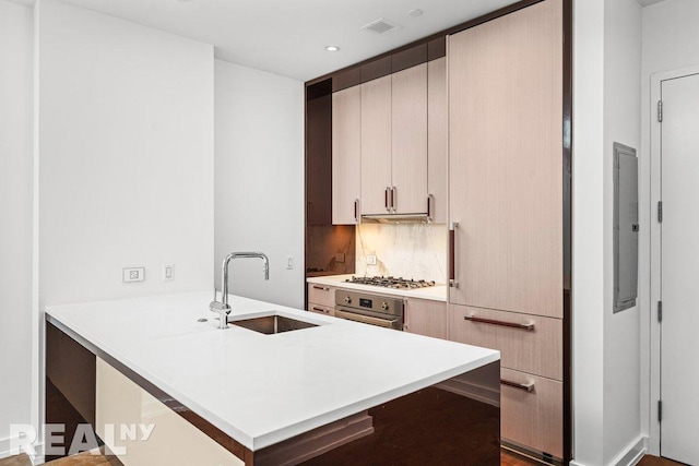 261 W 25th St Unit 8A, New York City, NY 10001 - kitchen with a sink, a peninsula, light countertops, tasteful backsplash, and gas stovetop